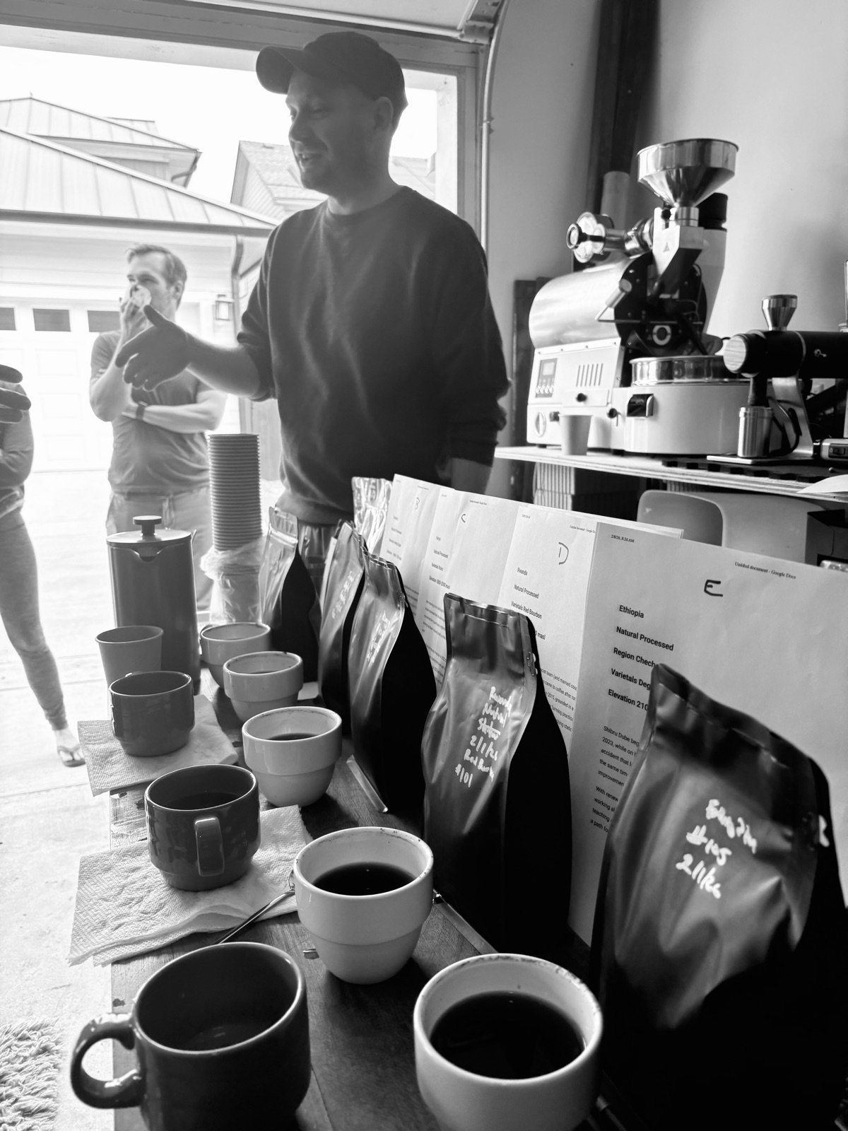 Cups of coffee lined up next to labelled bags and origin sheets